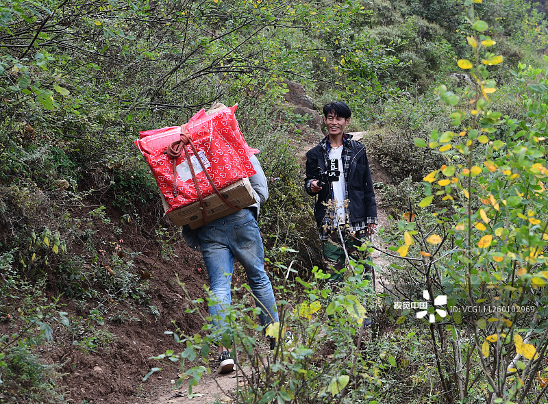 2019年11月16日，四川凉山，杨阳背包裹回家的路上遇见村里正在做直播的年轻人。