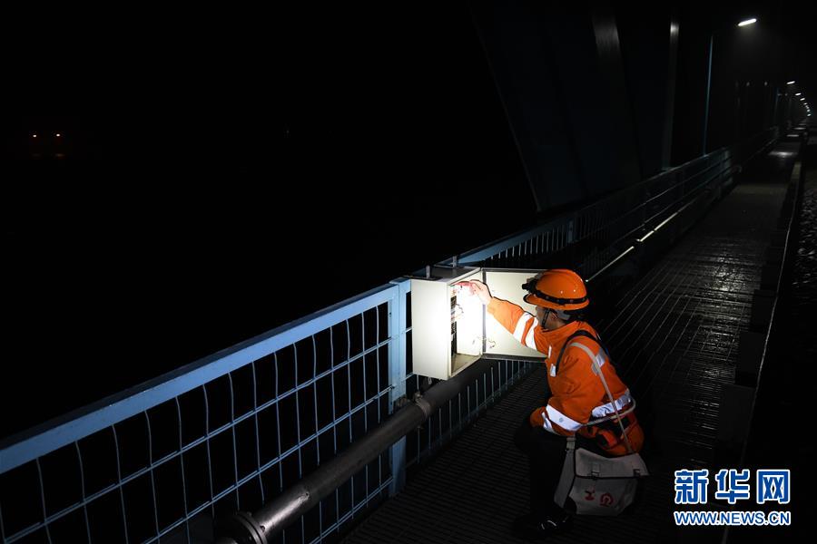1月10日凌晨，桥隧工张海洋在检查大桥配电箱内部电路及元件。 新华社记者 张端 摄
