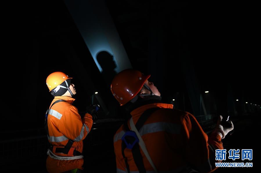 1月10日凌晨，两名桥隧工在检查大桥防落网。 新华社记者 张端 摄