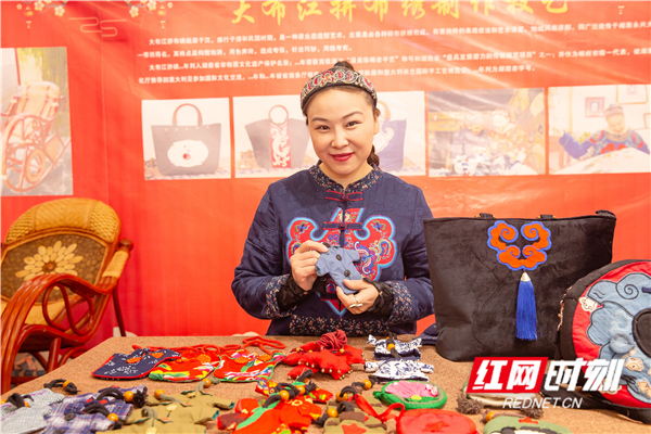 图为大布江拼布绣第五代传承人何娟老师展示着一件件精致的拼布绣产品。
