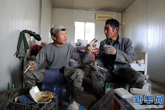 中午休息时间，付毛子和同伴在基地里休息、吃饭，交流采收成果。新华网 杨益民摄