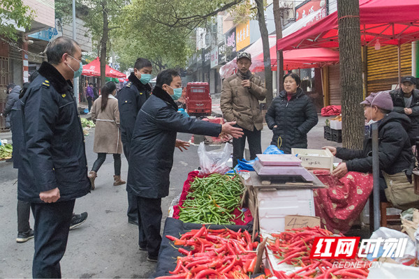 执法人员在建设路清理占道搭棚摆摊。