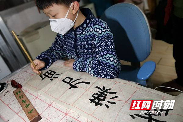 10岁的湛骐玮正在认真书写“武汉加油”.jpg