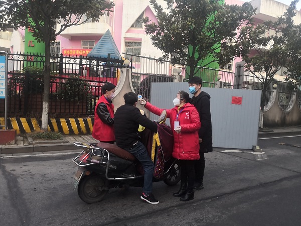 英才园小区实行封闭式管理，志愿者为入小区行人测体温.jpg