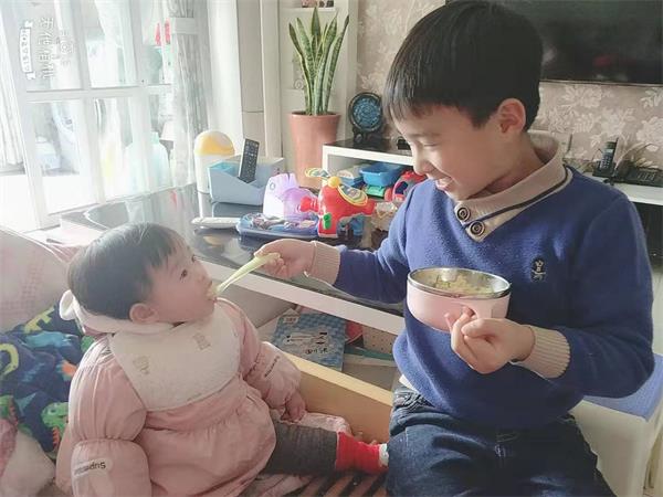 因疫情的原因，原本要上学的哥哥在家里学习，妹妹可开心啦，瞧！连吃饭都指定要哥哥喂，而且吃得特别棒！哥哥也不厌其烦，赶紧记录下这温暖的一刻。   拍摄者：熊劲 兰亭社区.jpg