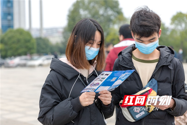 一对青年外出务工人员正在看企业招工宣传资料。（唐明登）