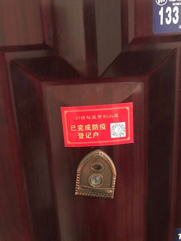 工作人员将“已完成防疫登记户”的标签贴在房门上.jpg