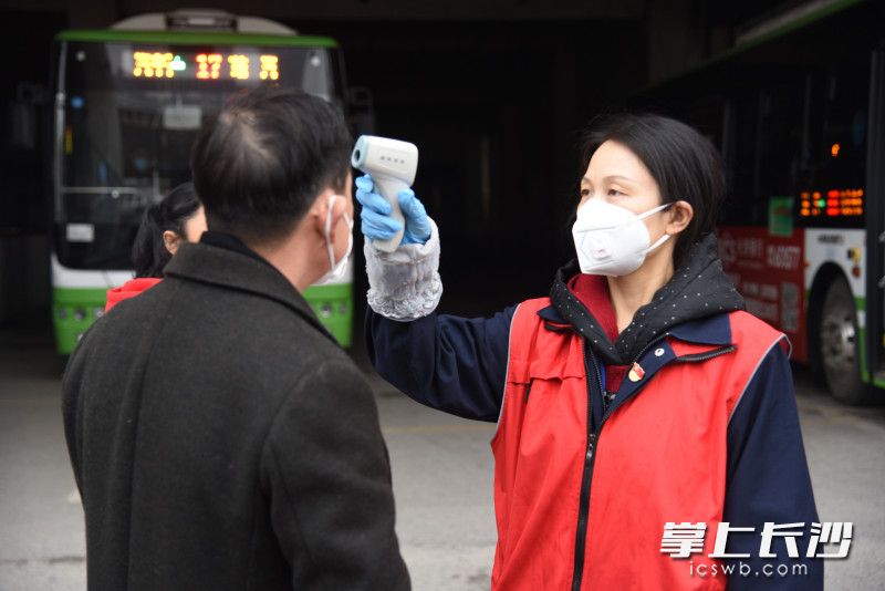 工作中，周敏一丝不苟，为乘客测量体温。