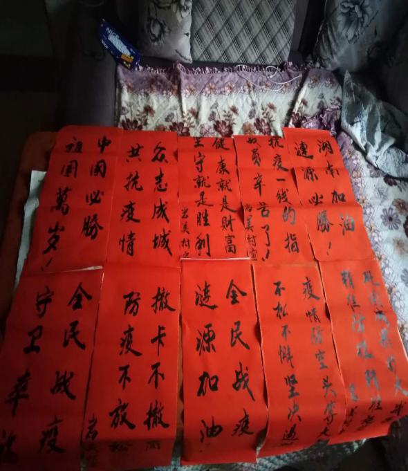 一边用毛笔在红纸上写下宣传