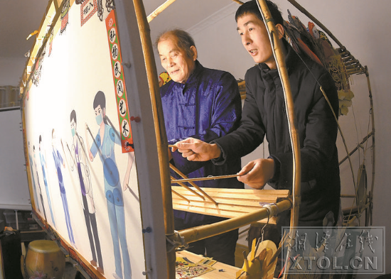 吴升平（左）和孙子吴渊（右）在表演抗“疫”纸影戏。 （记者 陈旭东 摄）
