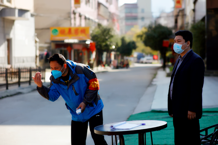 2月24日，湖南省资兴市东江街道罗围社区路口新冠病毒筛查点，值守的李智向进来的一辆车打着手势，要司机进来接受测量体温、出示小区居民出入证。