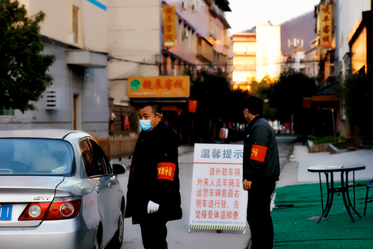 2月17日，曹文武在给进入小区的司机测体温，看出入证。