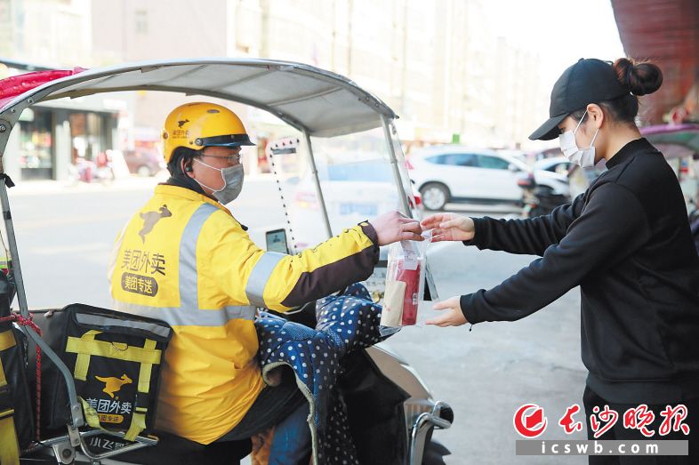 　　外卖又开始火了，宁乡一饮品店员将奶茶送到外卖小哥手中。刘静 摄