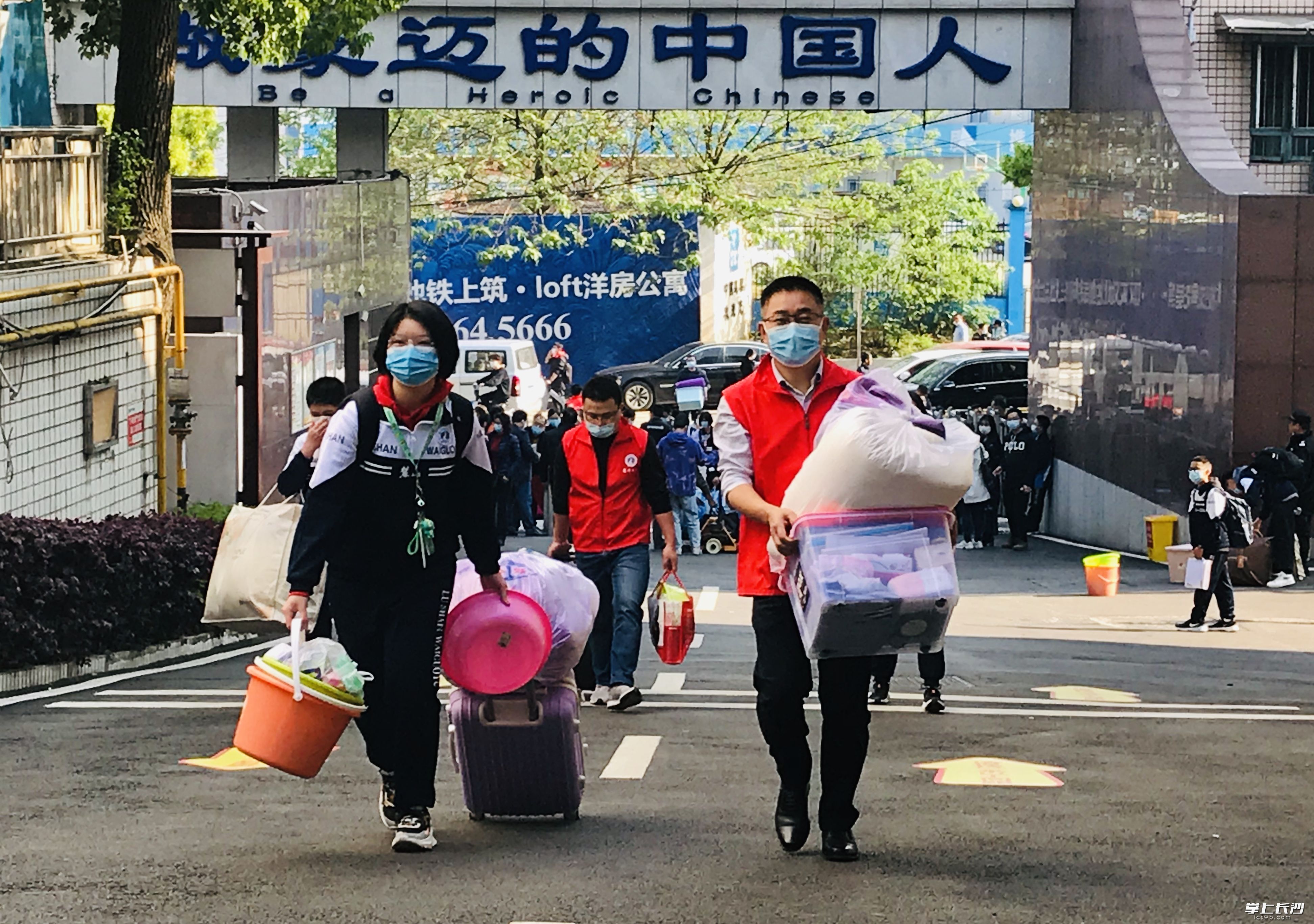 麓山外国语实验学校老师志愿者在帮学生搬运行李。