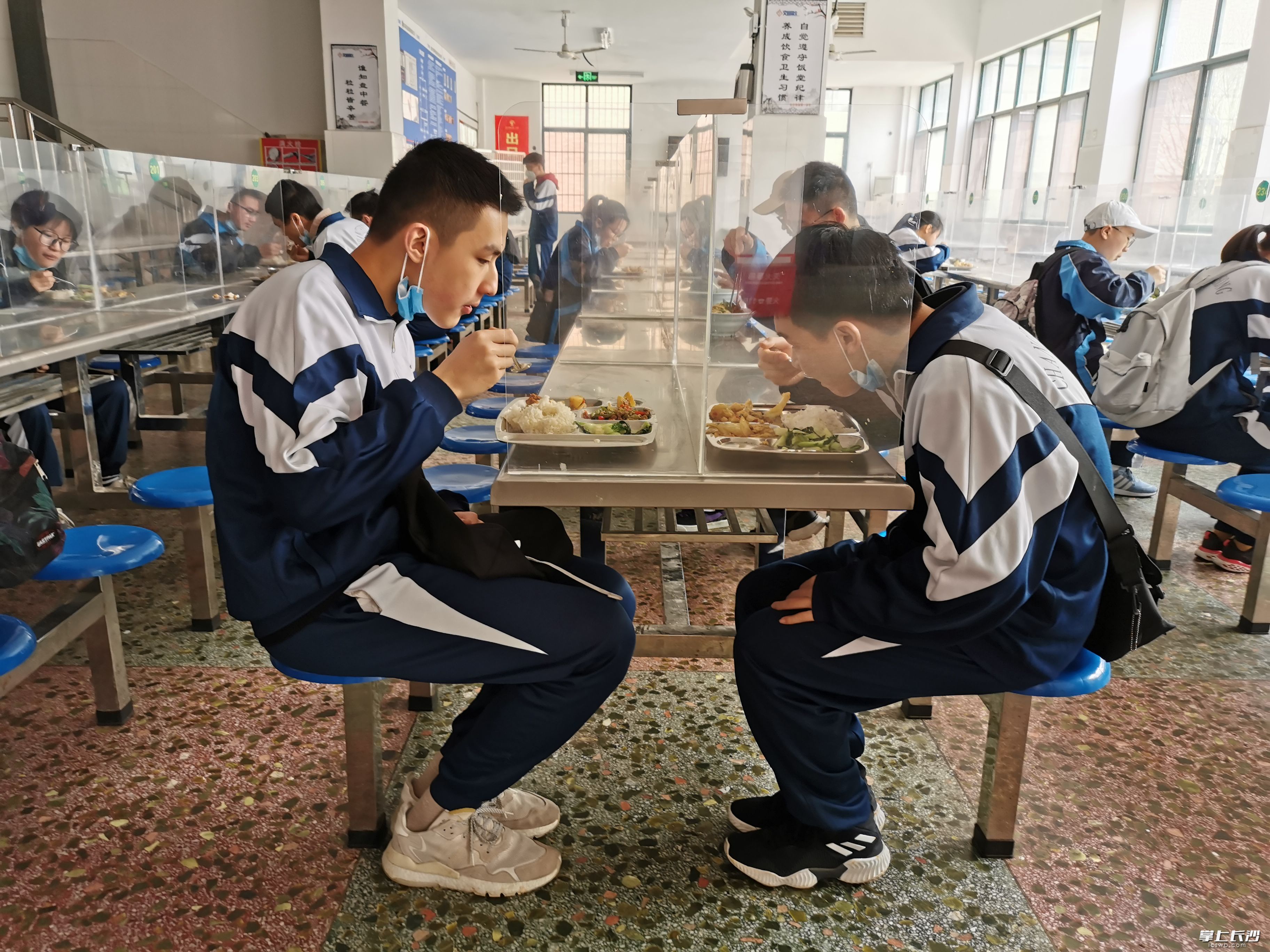 长铁一中学生在食堂就餐，餐桌用透明隔板隔开。