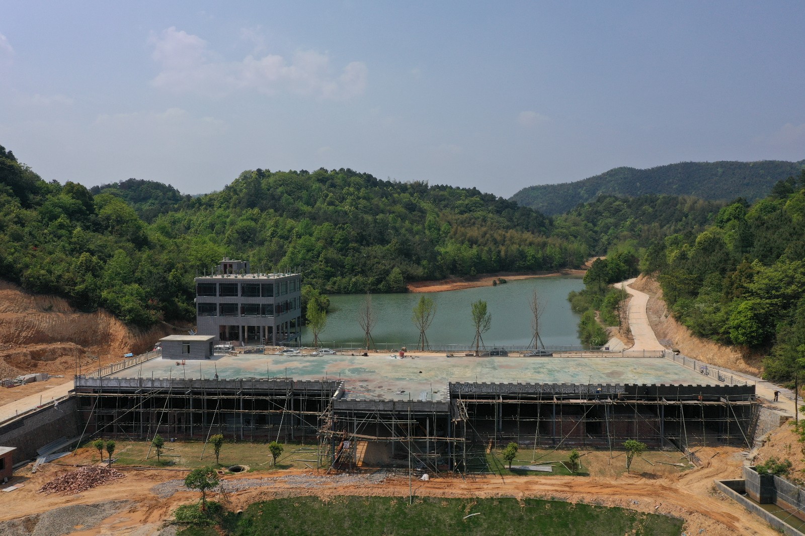 600亩的“金鲤湖”项目，近处是正在建设的农产品配送中心和餐饮接待中心，远处是湖面和山林。