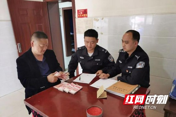 民警秦俊明、谌安将追回的赃款交还受害人。.marked.jpg