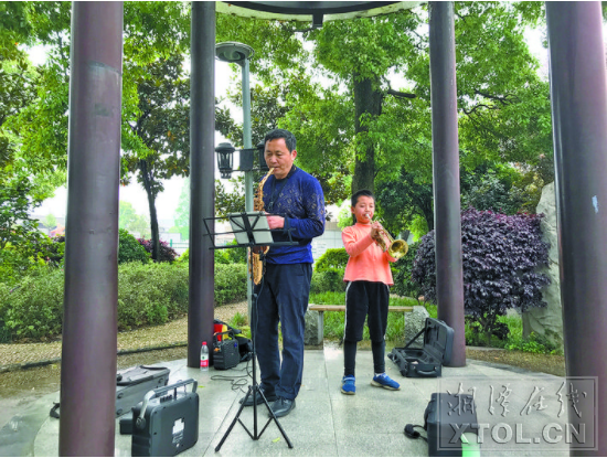 祖孙俩在岳塘公园练习演奏。 （记者 郑镱慧子 摄）