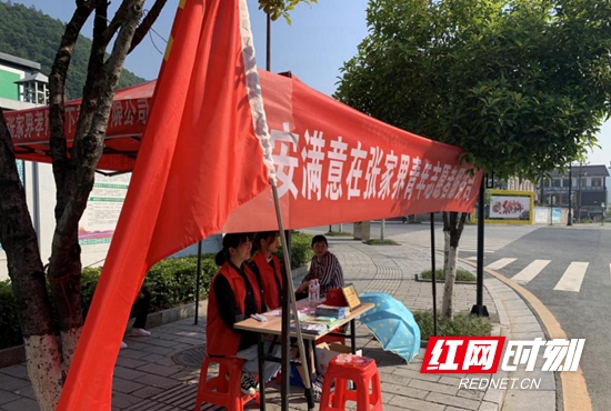 索溪峪街道牵手巾帼志愿服务队在喻家嘴三岔口咨询台服务游客.jpg