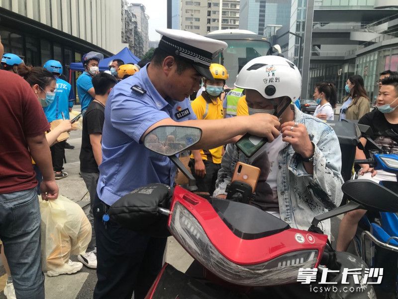 现场整治中，交警在对不带安全头盔的外卖小哥进行批评教育后，送上头盔。