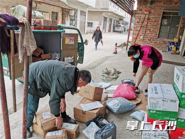 在宁乡市沙田乡石笋村，快递小哥按时将包裹快件送到超市，等候村民前来取件。长沙晚报通讯员林毅龙摄