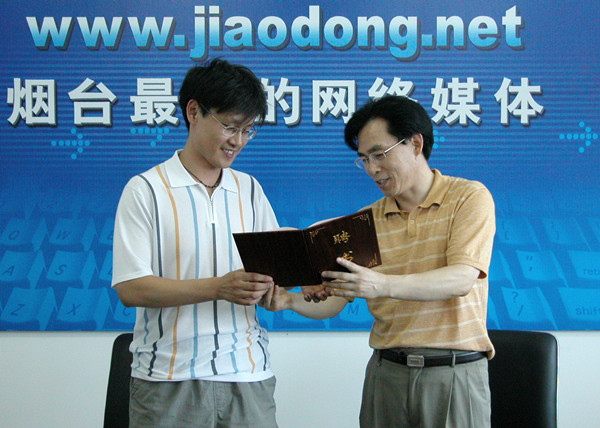 2005年7月,作者(右)给鲁东社区球迷俱乐部特邀技术顾问丁刚先生颁发聘书。