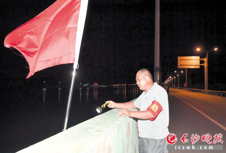 　　周师傅值晚班，他习惯拿着手电筒在河堤上看看。　　长沙晚报全媒体记者 邹麟 摄