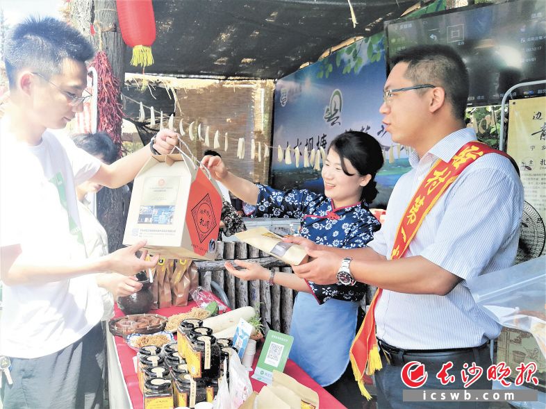 　　在扶贫集市上，作为非遗产品的龙田鲊肉颇受消费者青睐，驻横岭村帮扶第一书记夏振业（右一）也来热情推销。　　长沙晚报全媒体记者 张禹 摄