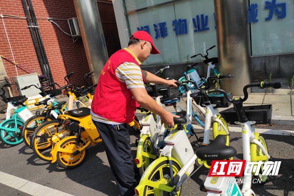 志愿者将道路两侧的共享单车整齐摆放.png