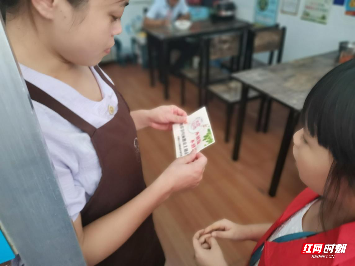 “睦邻·慧先锋”小小志愿者们在叮嘱餐馆服务员贴好标语