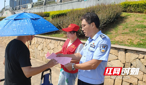 中国好人刘头仔在浏阳河边给钓鱼人发放“禁渔”宣传册并解释政策.jpg