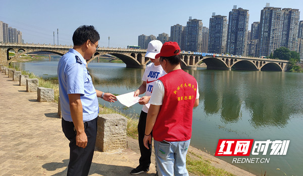 志愿者和刘头仔在浏阳河边给过往群众发放“倡议书”.jpg