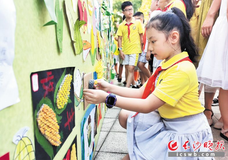 　　孩子们在“我是小米粒，来之不容易”展板上贴上一幅幅创意作品。 长沙晚报全媒体记者 舒文 摄