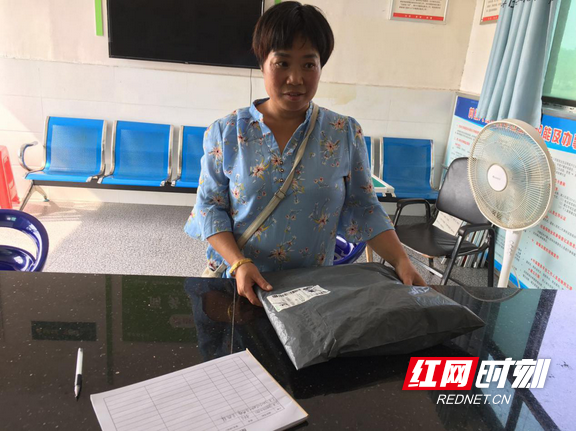 洞庭村村民匡热群到村部领取邮政快递。.marked.png