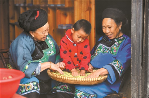 9月15日,66岁的村民龙美珍(右一)带着孙子,与邻居一起拉家常.