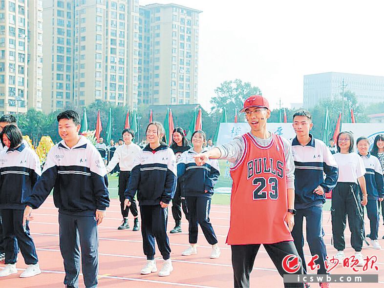 　　金亚骏（红衣）在校运会开幕式上和学生一起跳舞。  长沙晚报全媒体记者 刘俊 摄