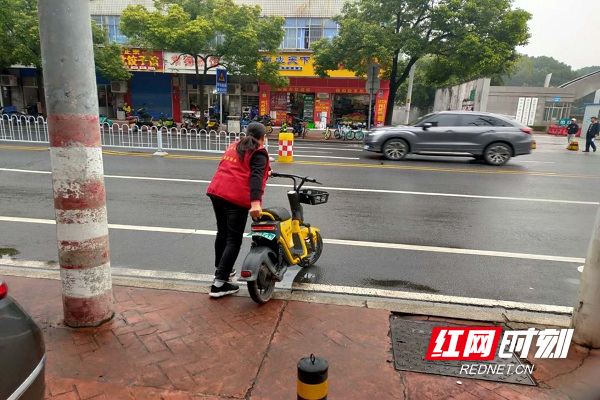 志愿者将无序停放的共享单车推到指定区域内。.jpg