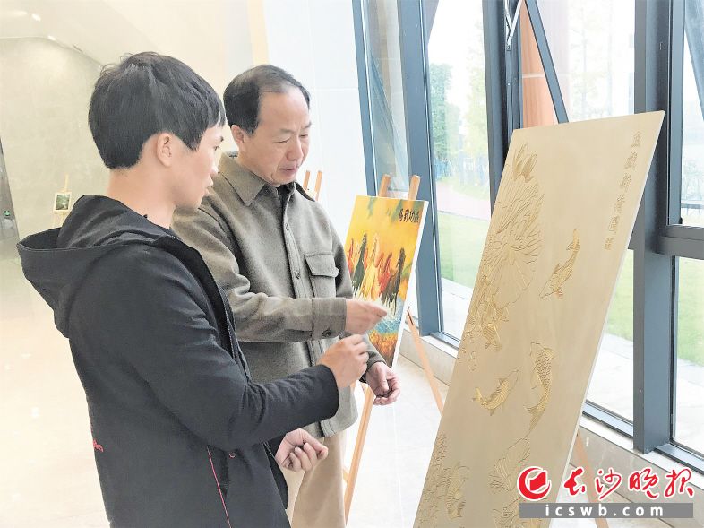 　　湖南省美术家协会主席朱训德（右）来到画展现场，对肖明进行指导。　　长沙晚报全媒体记者 张禹 通讯员 陈燕 摄影报道
