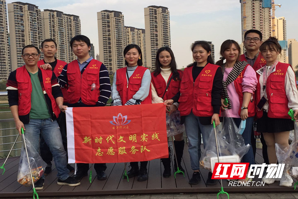 志愿者手持清洁工具在活动现场合影.png