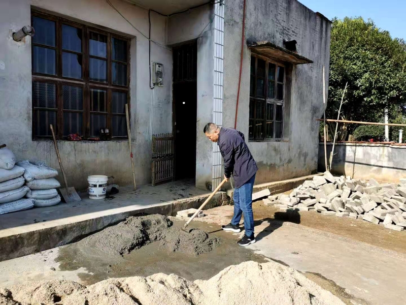 图为公司总经理苏双喜在贫困户家拌水泥浆