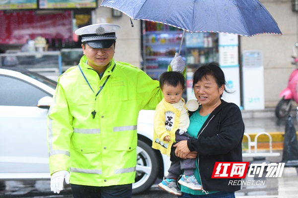 芙蓉交警大队民警郭翔雨中护送市民群众过马路.jpg