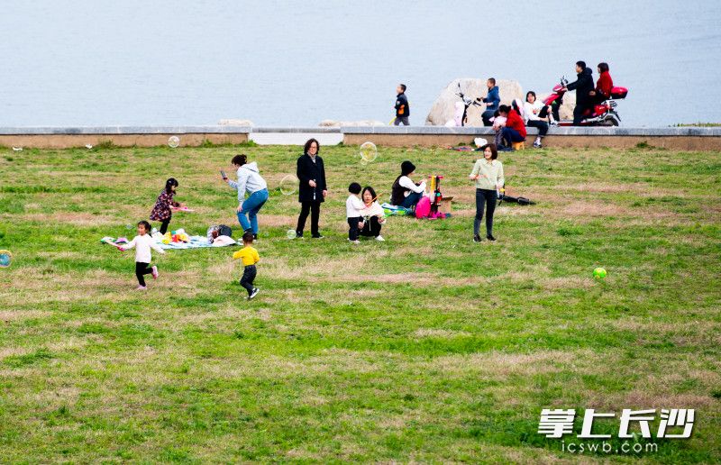 2月21日，，三汊矶大桥西湘江江滩上家长带着孩子正在追泡泡。