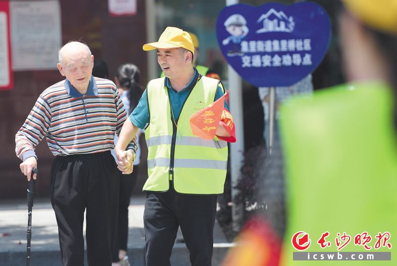 　　黄帽子雷锋志愿者汤勇（右）搀扶老人过马路。长沙晚报通讯员 彭红霞 摄