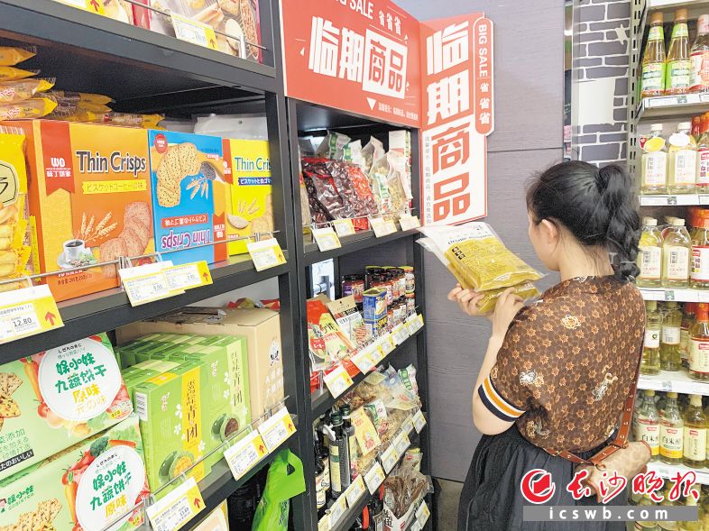 　　在长沙一家超市的临期商品柜，市民正在查看商品保质期。　　长沙晚报全媒体记者 范宏欢 摄