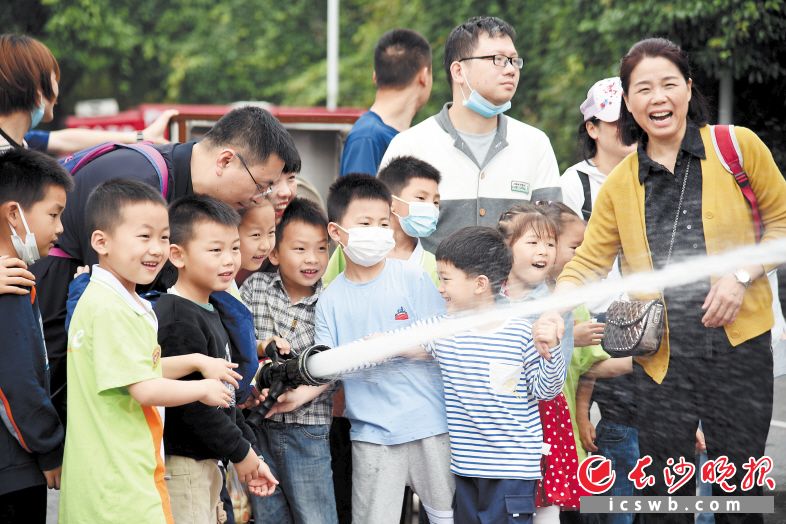 　　孩子在家长的陪同下，体验消防水枪出水“灭火”。　　长沙晚报全媒体记者 刘琦 摄