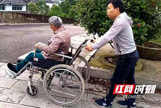 吴献海用轮椅推着下肢瘫痪的母亲散步。.jpg