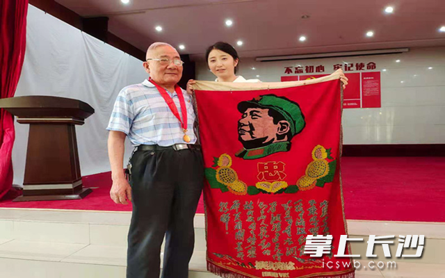 党员赵高鹏向与会党员展示当年在防空洞中完成的刺绣作品。