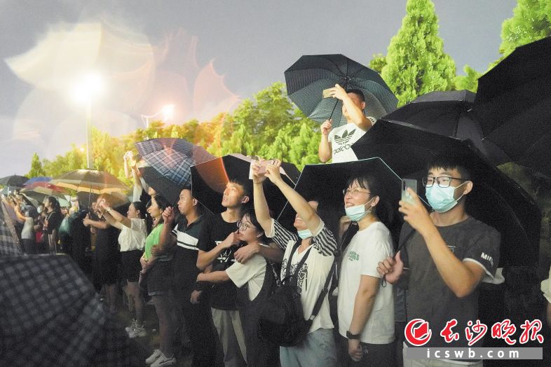 　　市民在雨中等待焰火晚会的到来。
