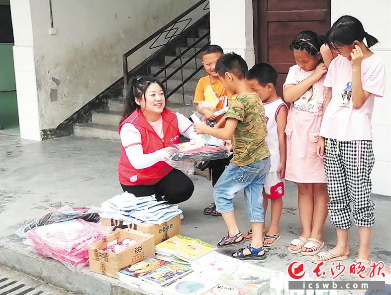 　　胡巧萍（左一）给雀儿寨小学的学生分发学习用品。受访者供图