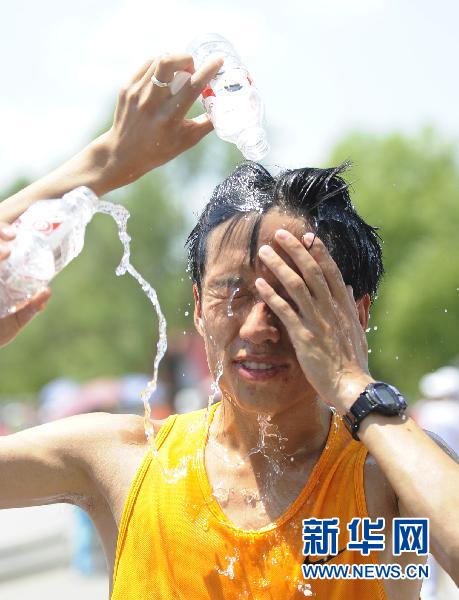 6月25日，一名市民在跑步后将水浇在头上解暑。